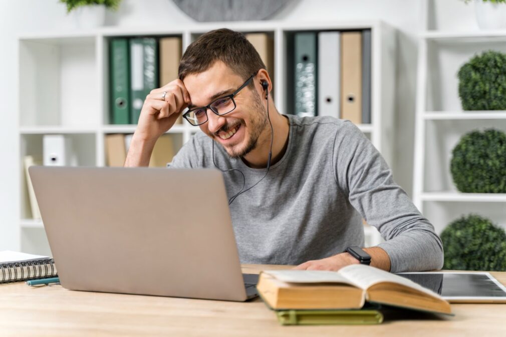 The man smiles and studies at his computer