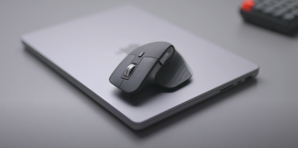 A black mouse resting on a silver laptop