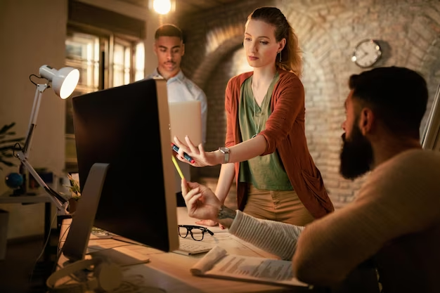 Two men and one woman working on a computer