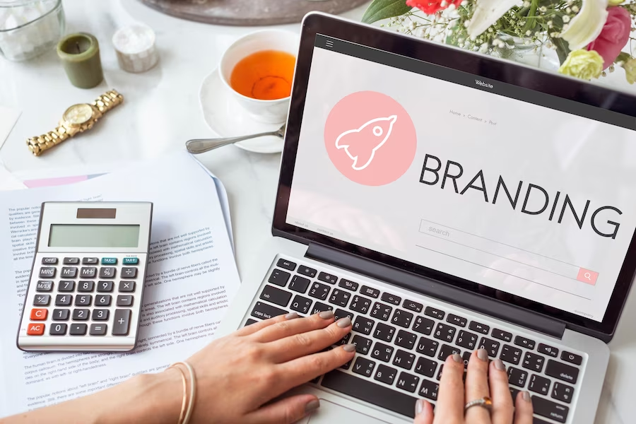 A woman using a laptop with the word "branding" on the screen