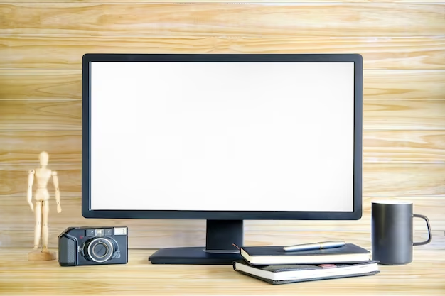 A desk setup with a computer monitor, notebooks, a camera, and a mug