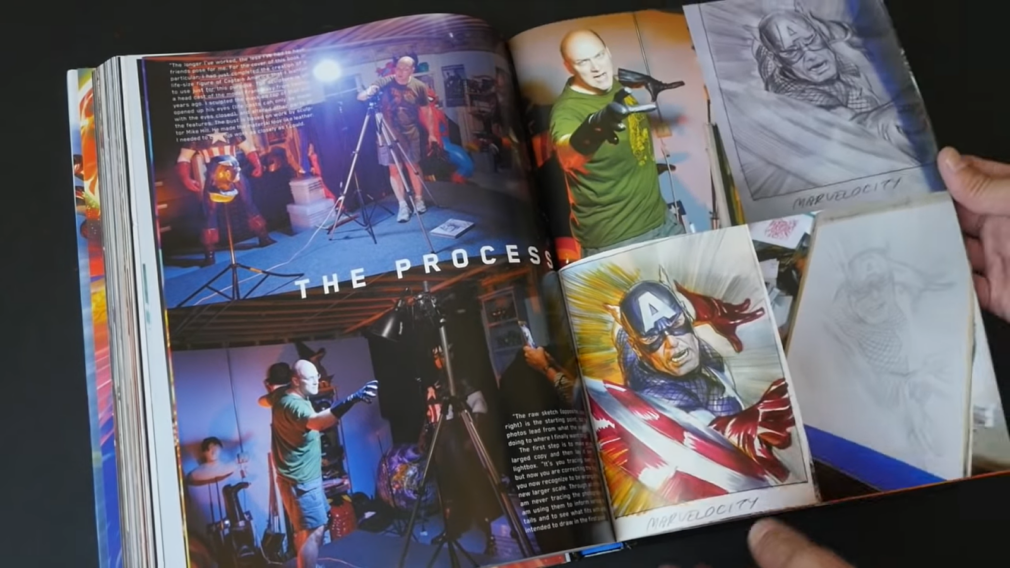 man holds opened marvelocity book with pictures of heroes