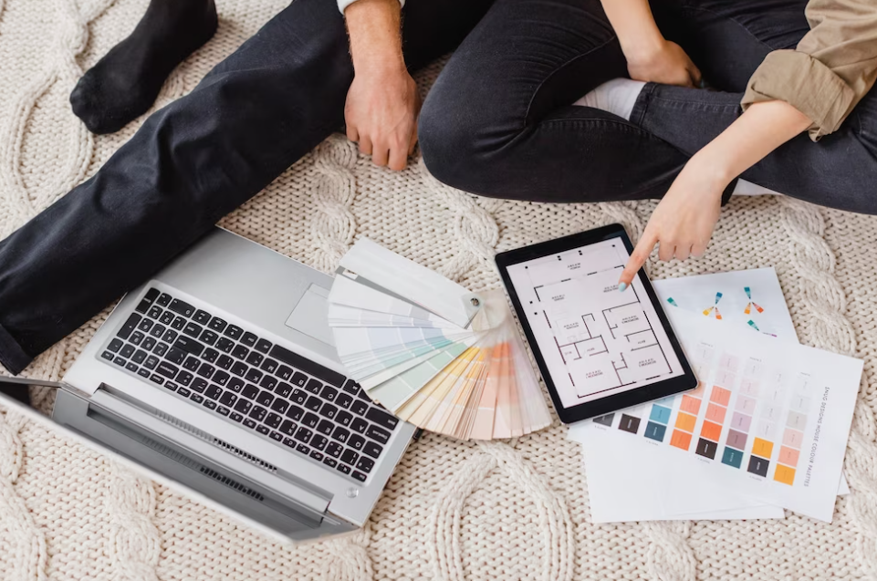 Woman and man sitting on a bed and looking at the laptop, color palette near them