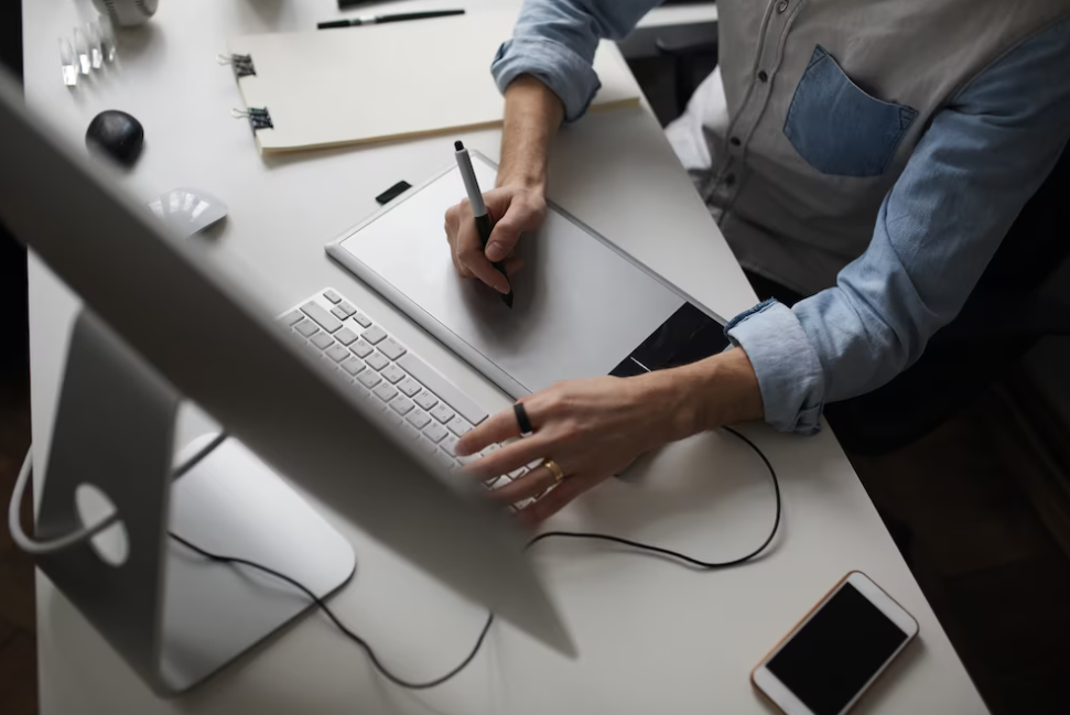 man’s hands typing on the keyboard, the phone and notebook on the table